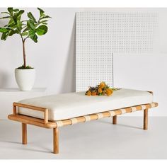 a wooden bench with a white cushion and potted plant