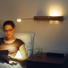 a woman sitting in bed reading a book at night with the light on her head