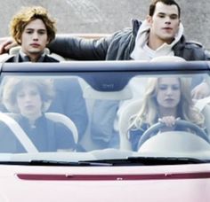 two people sitting in the back seat of a pink car, one is holding his arm up