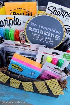 a basket filled with school supplies on top of a blue table next to a chalkboard