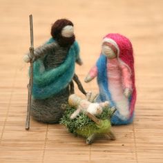 two small figurines are standing next to each other on a wooden surface, one is holding a stick