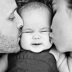 a man and woman kissing a baby with their noses close to each other