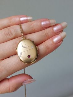 Beautiful and well-preserved Art Nouveau locket with fine engravings and a ruby paste in a heart-shaped inlay. It has a rosy gold color and semi-matte finish. Details: The locket dates from the Art Nouveau era, 1900s. It is not stamped and likely made of a gold plated metal. Condition: The locket is in excellent antique condition, with only very gentle surface wear and scratches. No dent. Inside one of the original rings and celluloid covers are present. It closes tightly with a snap. The bale i Antique Gemstone Jewelry For Memorial, Heirloom Jewelry For Valentine's Day, Heirloom Heart Cut Gemstone Jewelry, Red 14k Gold Engraved Jewelry, Valentine's Day Fine Jewelry Locket, 14k Gold Red Engraved Jewelry, Red Engraved 14k Gold Jewelry, Valentine's Day Yellow Gold Locket Jewelry, Valentine's Day Yellow Gold Locket