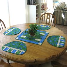 a wooden table with four placemats and a potted plant sitting on top of it