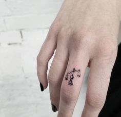 a person's hand with a tattoo on it that has a scale and arrow