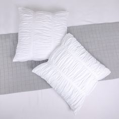 two white pillows sitting on top of a bed next to a gray and white blanket