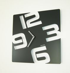 a clock that is on the side of a wall with white letters and numbers around it