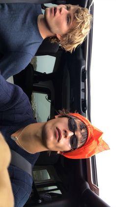 two young men standing next to each other in front of a car with sun glasses on