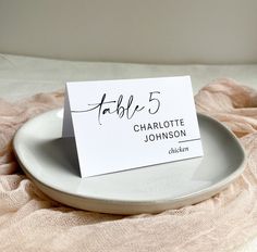 a white plate with a place card sitting on top of it next to a pink blanket