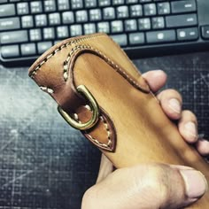 a person holding a leather case in front of a keyboard