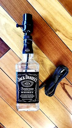 a bottle of jack daniels whiskey sitting on top of a wooden floor next to a charger