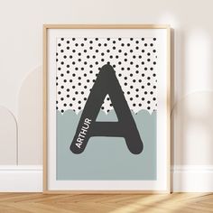 a black and white polka dot alphabet print on a wall next to a wooden frame