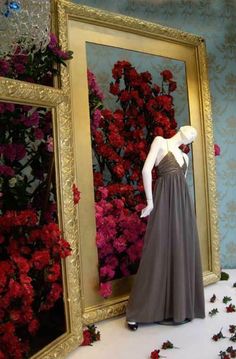 a mannequin is standing in front of a large mirror with flowers on it