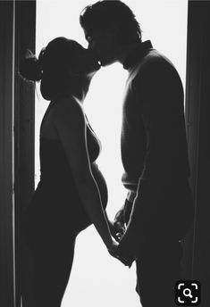 a man and woman kissing in front of a window