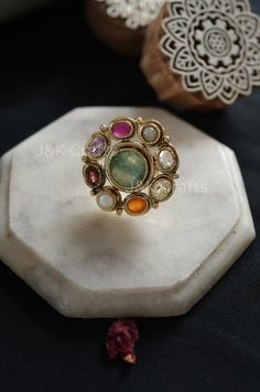 Skillfully made using classic methods, the ring features a fragile design embellished with semi-precious navrattan gemstones and the radiance of multicolored stones. These stones impart a touch of sophistication to this timeless treasure. Enhance your fashion with this exceptional ring. Closure - Adjustable Weight- 17gms Handcrafted in Jammu and Kashmir Paisley Pop travels the depths of India to learn techniques and crafts from deep down in the local markets and villages. We give utmost importance to our quality and packaging. Our goal is to ensure you receive exactly what you are looking for and for your experience to be special and memorable. We are ready to help and advise you through your purchase. IT' S  A W E S O M E * Our lovely packaging is designed by our co-founder Tanya. And all Luxury Elegant Meenakari Rings, Elegant Multicolor Ruby Ring, Luxury Multicolor Rings With Center Stone, Elegant Multicolor Rings For Anniversary, Multicolor Heirloom Rings For Formal Occasions, Elegant Multicolor Gemstones With Center Stone, Heirloom Multicolor Rings For Formal Occasions, Heirloom Multicolor Rings For Formal Events, Elegant Multicolor Multi-stone Emerald Ring