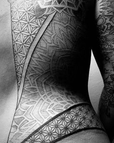 black and white photograph of a man's back with intricate tattoos on his body