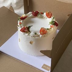 a white cake with strawberries on top in a box