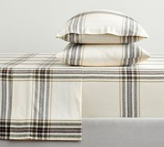 three pillows are stacked on top of each other in front of a plaid bed spread