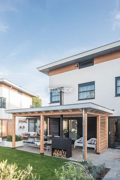 a modern house with an outdoor kitchen and living area in the back yard, surrounded by greenery