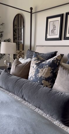 a large bed with pillows on top of it in a bedroom next to two framed pictures