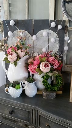 a table topped with vases and flowers on top of a wooden dresser next to a mirror