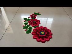 two red flowers are on the floor with green leaves and one is made out of felt