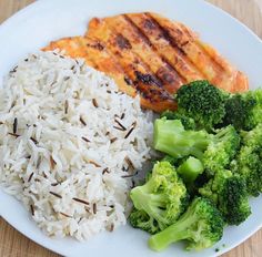 a white plate topped with rice, broccoli and chicken