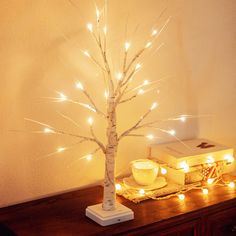 a small tree with lights on it sitting on top of a wooden table next to a box