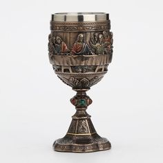 an ornately decorated silver goblet with pictures on the outside and inside it