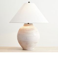 a white lamp sitting on top of a table next to a white wall and floor