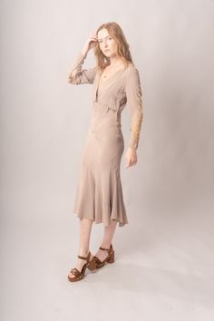 Stunningly preserved 1920’s mauve & ecru bias cut dress with attached jacket, lace trim, and asymmetrical cut. Best fits modern size S-M Length 52”Pit to pit 18.5”Waist 26-30”Hips 31-42” Model’s Measurements:Height 5’9”Chest 34”Waist 29”Hips 36.5” Excellent vintage condition, with normal wear and condition for its age.For international shipping rates, please send inquiries to our CONTACT page. Fitted Bias Cut Midi Dress For Daywear, Fitted Lace Trim Midi Dress For Fall, Daywear Fitted Bias Cut Dresses, Fitted Bias Cut Dresses For Daywear, Bias Cut Fitted Daywear Dresses, Bias Cut Fitted Dresses For Daywear, Fitted Bias Cut Dresses For Fall, Fitted Taupe V-neck Dress, Taupe Fitted V-neck Dress