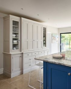 a kitchen with white cabinets and blue island