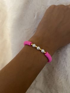 a woman's arm wearing a pink bracelet with pearls and gold beads on it