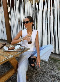 a woman sitting at a table holding a drink