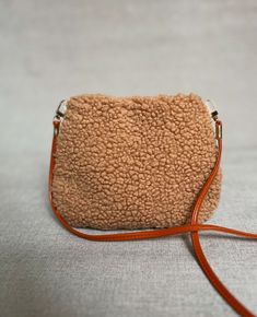 a small purse is sitting on the floor next to a white tablecloth with a brown leather strap