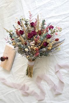 a bouquet of flowers sitting on top of a white table cloth next to a book