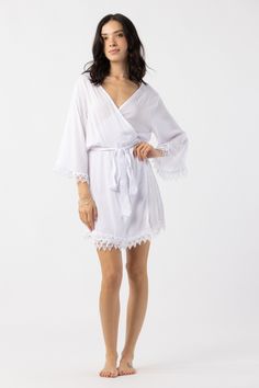 The Sunset Robe transforms relaxing moments into pure bliss. This rayon robe was designed with delicate crochet lace trim lines the waist and sleeves, adding elegance and ornate detail. Embroidered by hand, the intricate cutwork detail exudes craft and old world love. Details: 100% Rayon Hand Wash & Lay flat to dry Features: Unlined, Embroidery throughout sleeves and hemline White Lace Robe With Lace Trim, Elegant Lace Trim Sleepwear For Vacation, White Lace Trim Robe For Summer, White V-neck Kimono For Daywear, White Kimono With Lace Trim, Delicate Lace Sleepwear For Beach, Summer Robe With Lace Trim For Daywear, Elegant Summer Robe With Lace Trim, White Lace Loungewear Dress