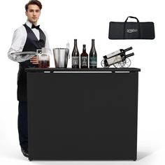 a man standing behind a bar with bottles and glasses on it, holding a tray