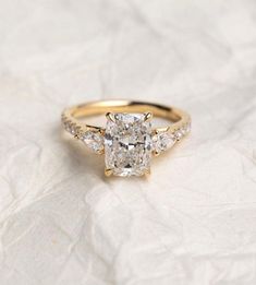 an engagement ring with three stones on it and a diamond band around the band, sitting on a white surface