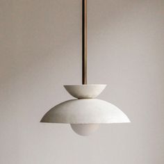 a white lamp hanging from a ceiling in a room with no one around it and the light is on