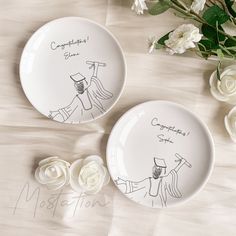 two white plates with drawings on them next to flowers