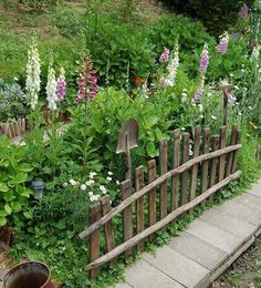 a garden filled with lots of flowers next to a wooden fence