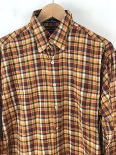 a brown and yellow plaid shirt hanging on a hanger