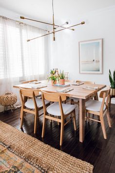 the dining room table is set with six chairs and a potted plant on it