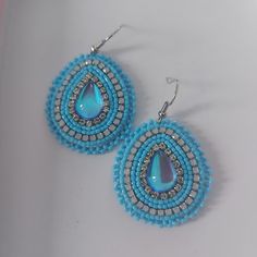 a pair of blue and white beaded earrings with tears on top of them