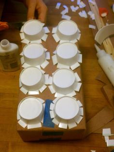 the table is covered with white plates and paper on it's surface, ready to be cut into smaller pieces