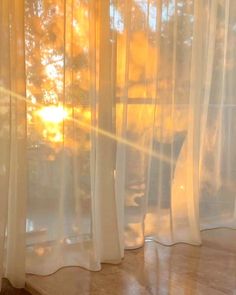 the sun is shining through the sheer curtains