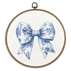 a blue and white bow is hanging from a hoop on a wall mounted embroidery project