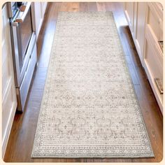 a large rug is in the middle of a kitchen with white cabinets and wood floors