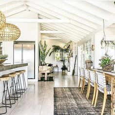 a dining room table and chairs in front of a bar with potted plants on it